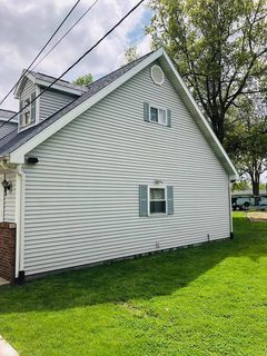 outside siding on side of house with two windows with green grass in front